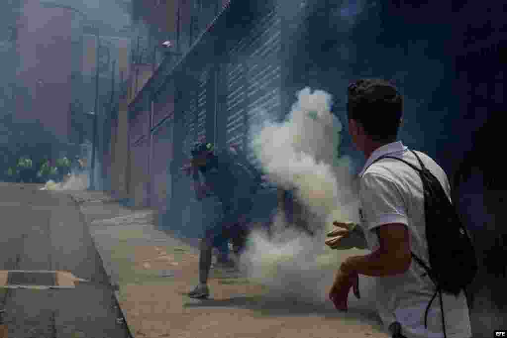 Manifestantes evaden gases lacrimógenos lanzados por miembros de la Policía Nacional Bolivariana (PNB).