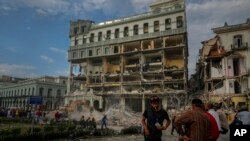 Personas observando los trabajos de rescate luego de una explosión letal que dañó el hotel Saratoga, en La Habana, el viernes 6 de mayo de 2022. (AP Foto/Ramón Espinosa)