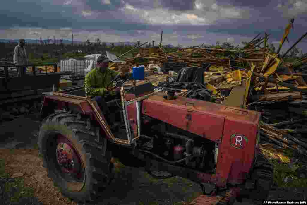 El productor de tabaco Hirochi Robaina conduce su tractor frente a graneros de tabaco destruidos en su finca una semana después del huracán Ian en San Luis, en la provincia de Pinar del Río. 