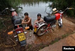 Un grupo de jóvenes lavan sus motocicletas en el Río Guanímar.