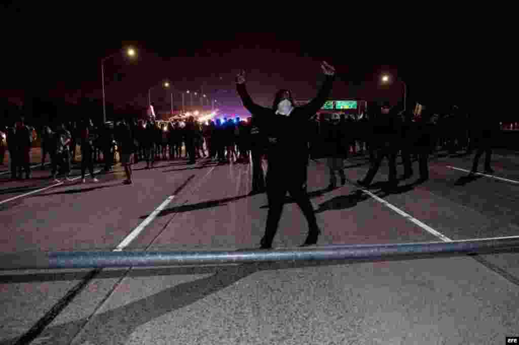 Un manifestante celebra tras haber ayudado a volcar una farola para cortar una carretera mientras varios activistas bloquean el tráfico en la autopista HWY 580 durante una protesta en Oakland, California, contra la elección del republicano Donald Trump como presidente de EEUU. 
