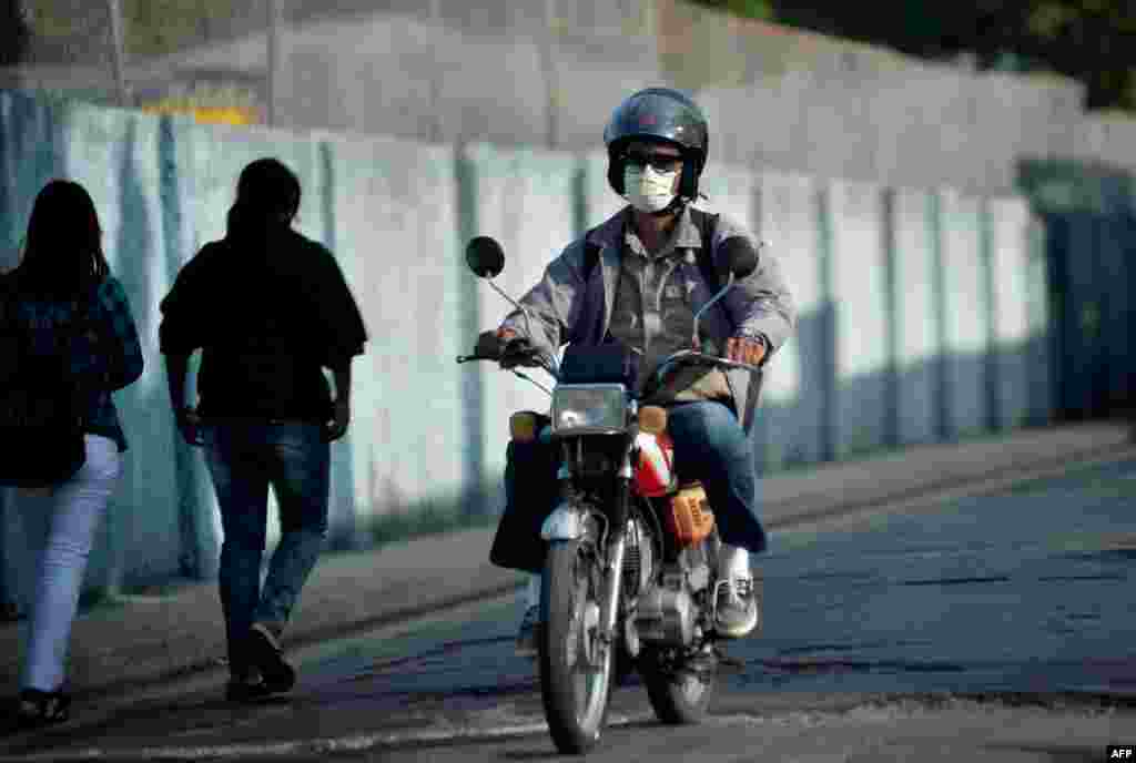 Un hombre usa una máscara facial mientras conduce una moto en La Habana.