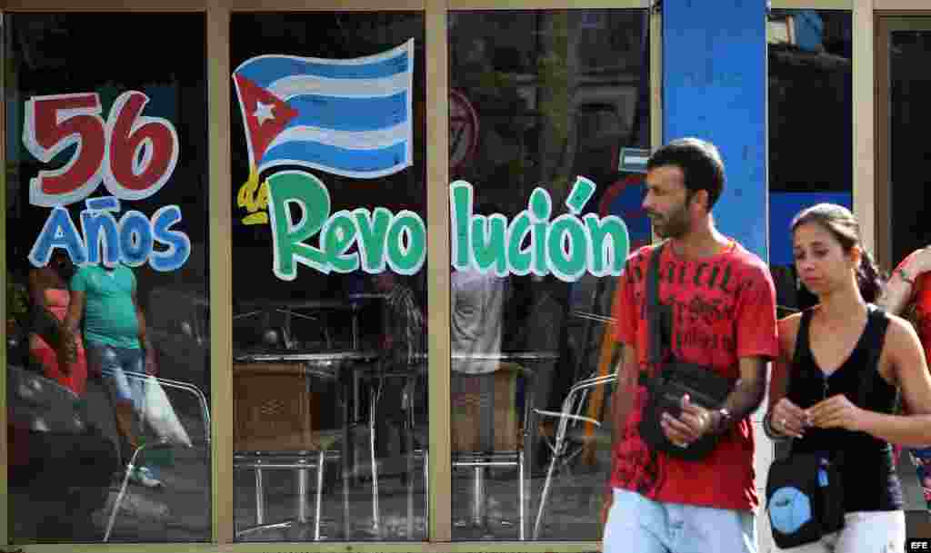 Una pareja camina hoy, miércoles 31 de diciembre de 2014, frente a un grafiti alusivo al nuevo aniversario de la Revolución cubana, en La Habana (Cuba).