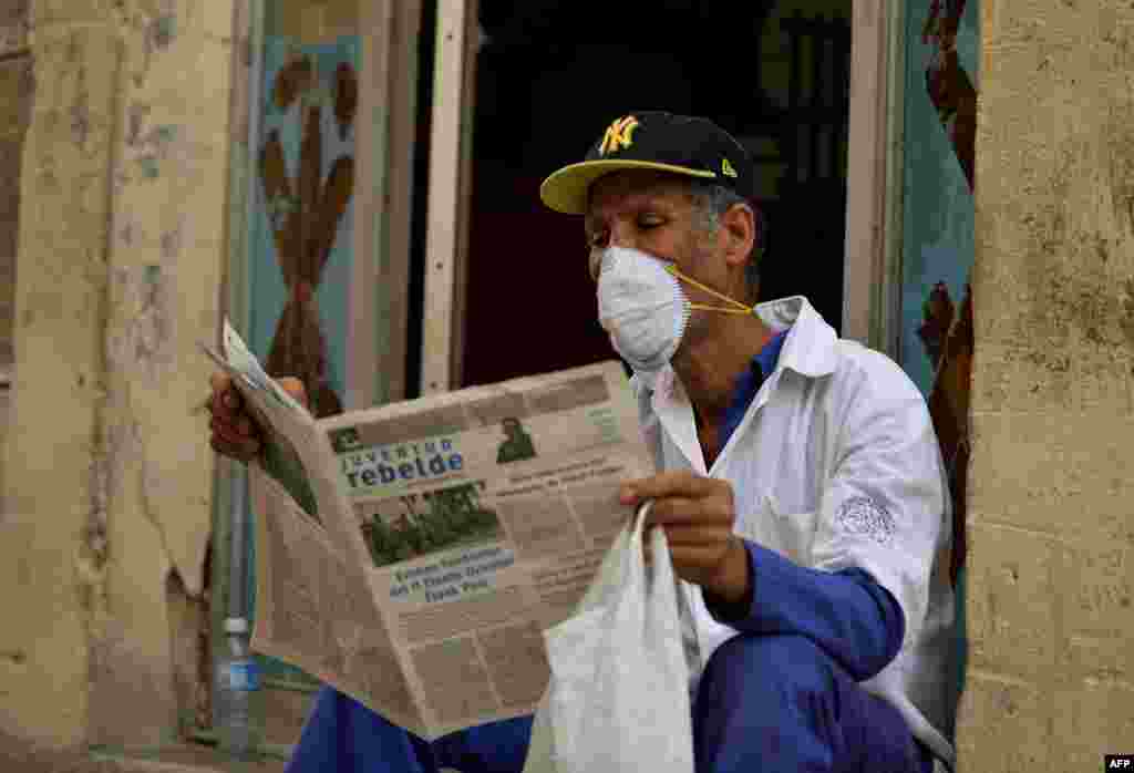 Un hombre lee un periódico mientras usa una máscara facial