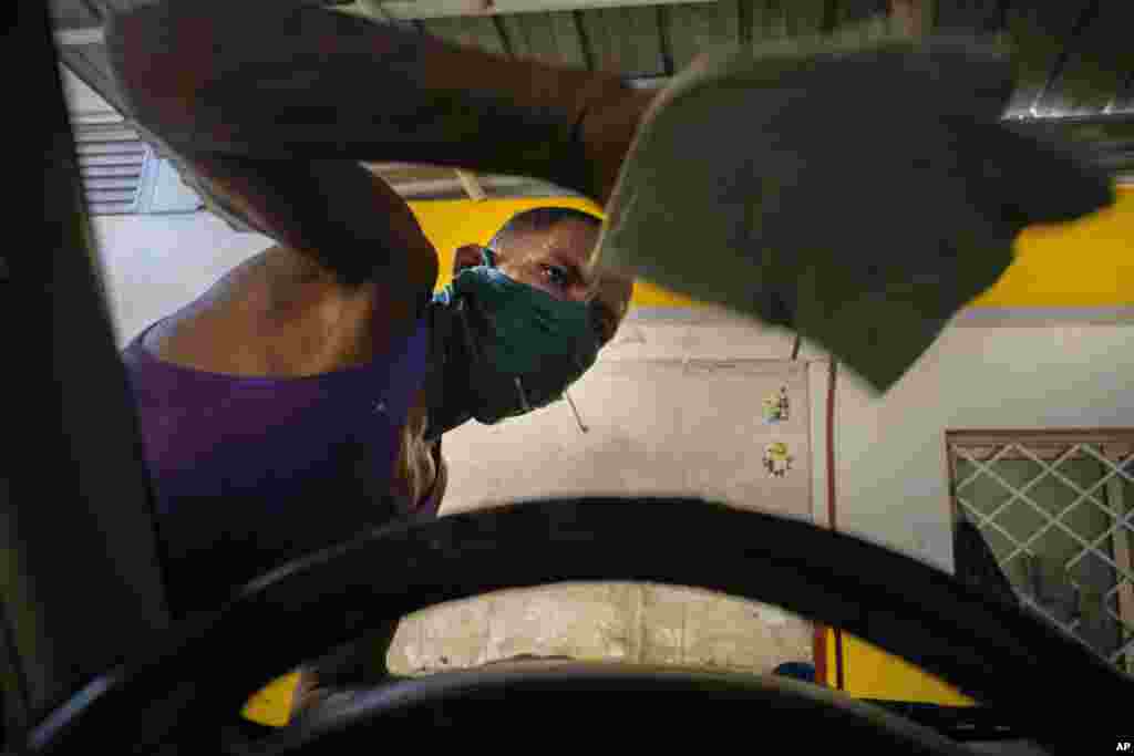 Un trabajador que usa una máscara como precaución en medio de la propagación del coronavirus limpia un parabrisas en un lavado de autos en La Habana. (AP/Ramón Espinosa)