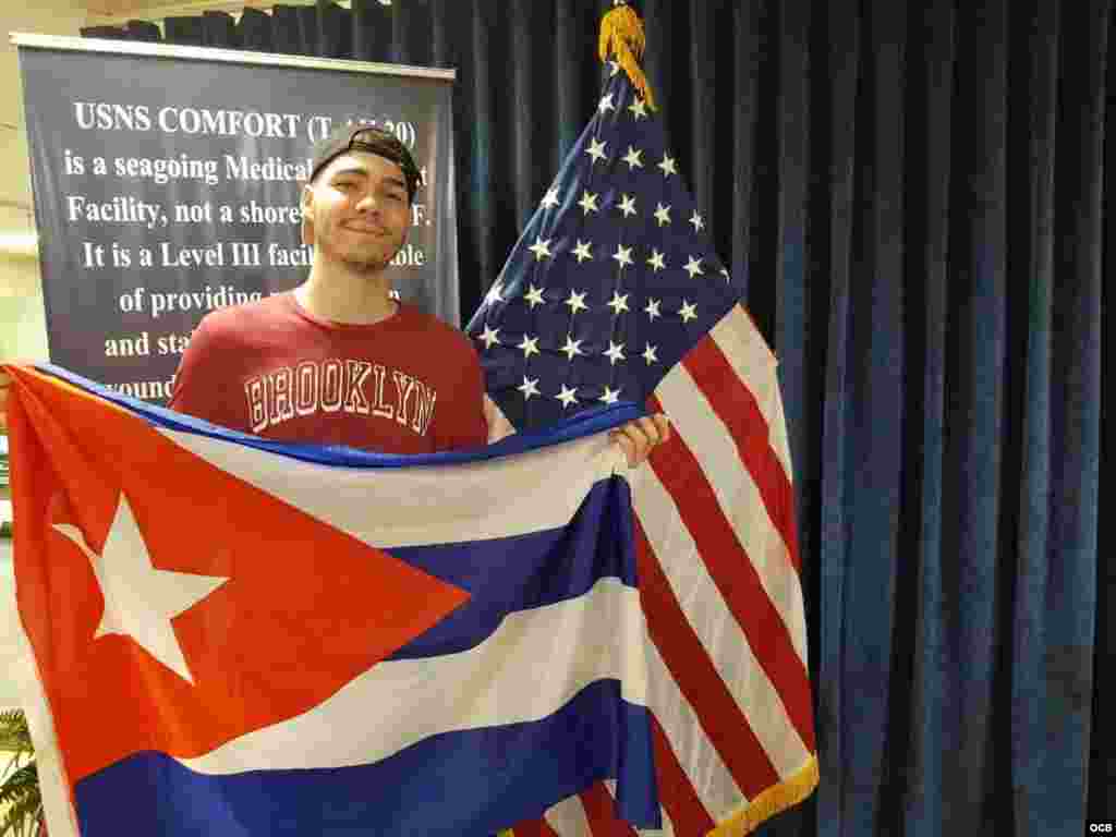Erick Reyes "Cuco" despliega la bandera cubana en el buque hospital de EEUU en señal de agradecimiento.