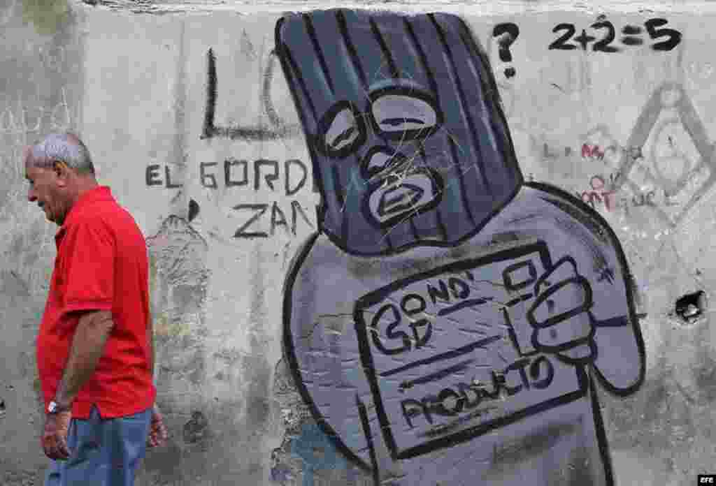 Un hombre camina junto a un grafiti alusivo a la libreta de abastecimiento en una calle de La Habana (Cuba), este viernes, 20 de enero de 2017, día en que Donald Trump asume la presidencia de EEUU. Washington y La Habana han desarrollado una frenética actividad bilateral en las últimas semanas, pues con la salida de Barack Obama de la Casa Blanca y la llegada de Trump la continuidad del deshielo iniciado en el 2014 se tiñe de incertidumbre, dado que el nuevo mandatario ha insistido en que no está de acuerdo con este proceso. 
