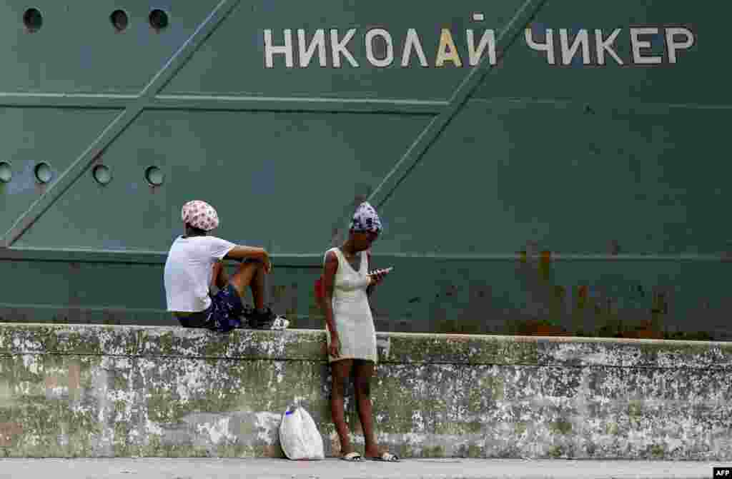 Personas permanecen frente al remolcador de rescate y salvamento Nikolai Chiker, parte del destacamento naval ruso que visita Cuba, tras su llegada al puerto de La Habana el 12 de junio de 2024. YAMIL LAGE / AFP
