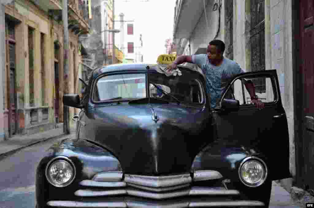 Un hombre limpia su taxi antes de iniciar labores en una calle de La Habana (Cuba), este viernes, 20 de enero de 2017, día en que Donald Trump asume la presidencia de EEUU. 