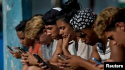 Jóvenes cubanos se conectan a internet desde su teléfono móvil en La Habana. Una de las quejas de los ciudadanos después de la llegada de internet móvil a la isla es que la conectividad es demasiado cara, lenta y censurada por el régimen. (YAMIL LAGE / AFP)