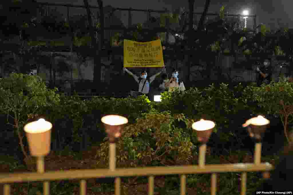 Un oficial de policía sostiene una pancarta para advertir a la gente que enciende velas en las afueras de Victoria Park, en Hong Kong, para conmemorar los sucesos de Tiananmen, en su 32 aniversario.