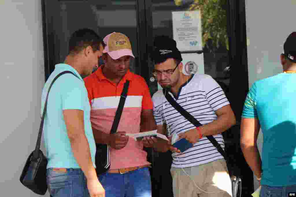Tres cubanos revisan sus documentos hoy, miércoles 10 de febrero de 2016, que les permiten comprar el boleto de avión, por 523,50 dólares cada uno, para viajar a México.