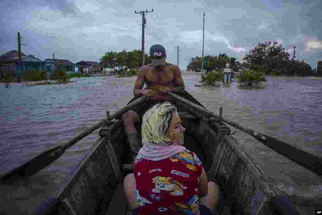 Cubanos recorren una calle inundada en un bote de madera en Guanimar, provincia de Artemisa, donde varias localidades quedaron bajo el agua tras el pasod el huracán Helene, el miércoles 25 de septiembre de 2024. (Foto AP/Ramon Espinosa)