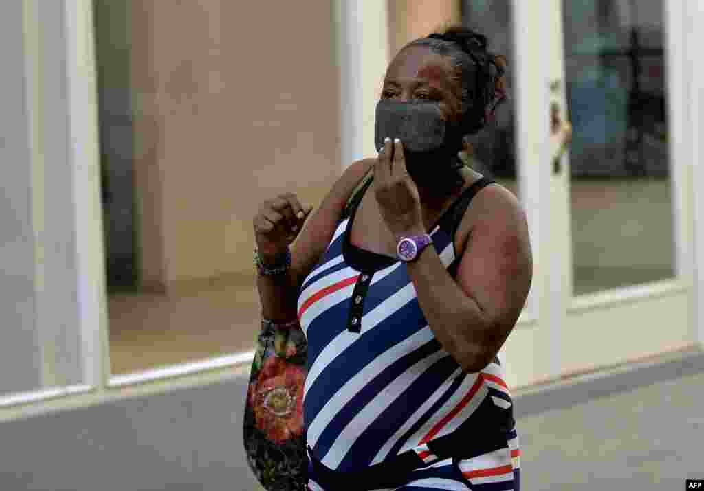 Una mujer cubana con una máscara protectora camina por una calle de La Habana.