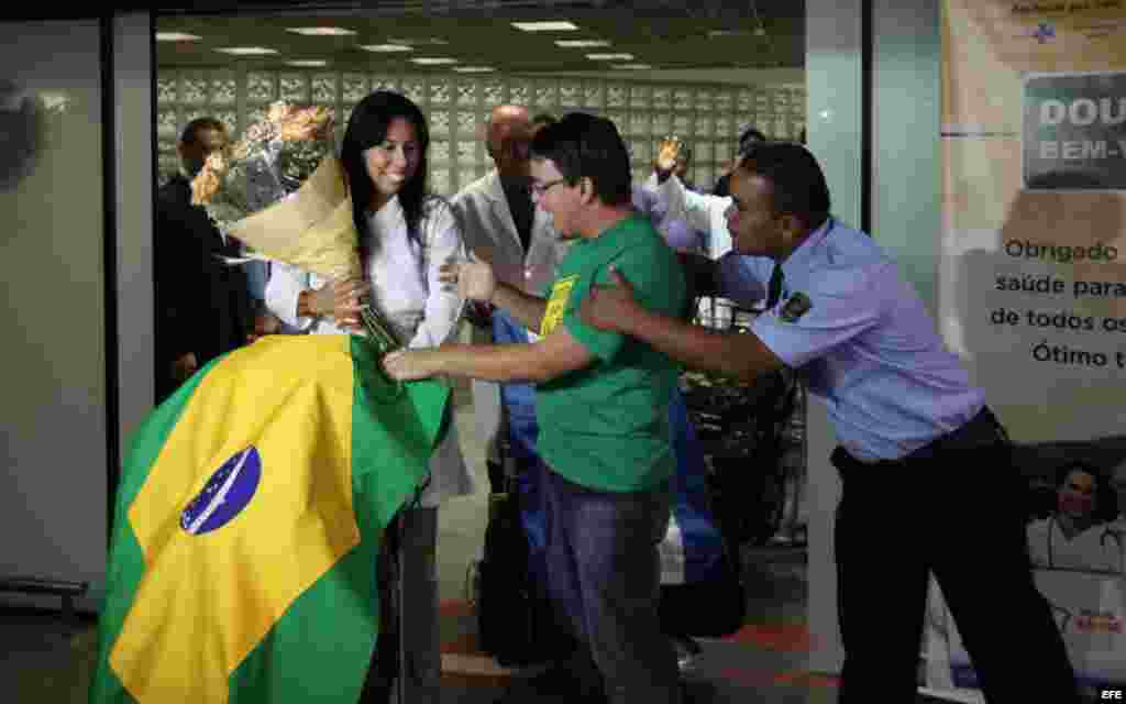 La médica cubana Yaisel Perea (i) es recibida por manifestantes que apoyan la llegada de doctores de Cuba al país, durante una recepción para un grupo de 200 profesionales hoy, sábado 24 de agosto de 2013, al aeropuerto de Brasilia. La presidenta brasile