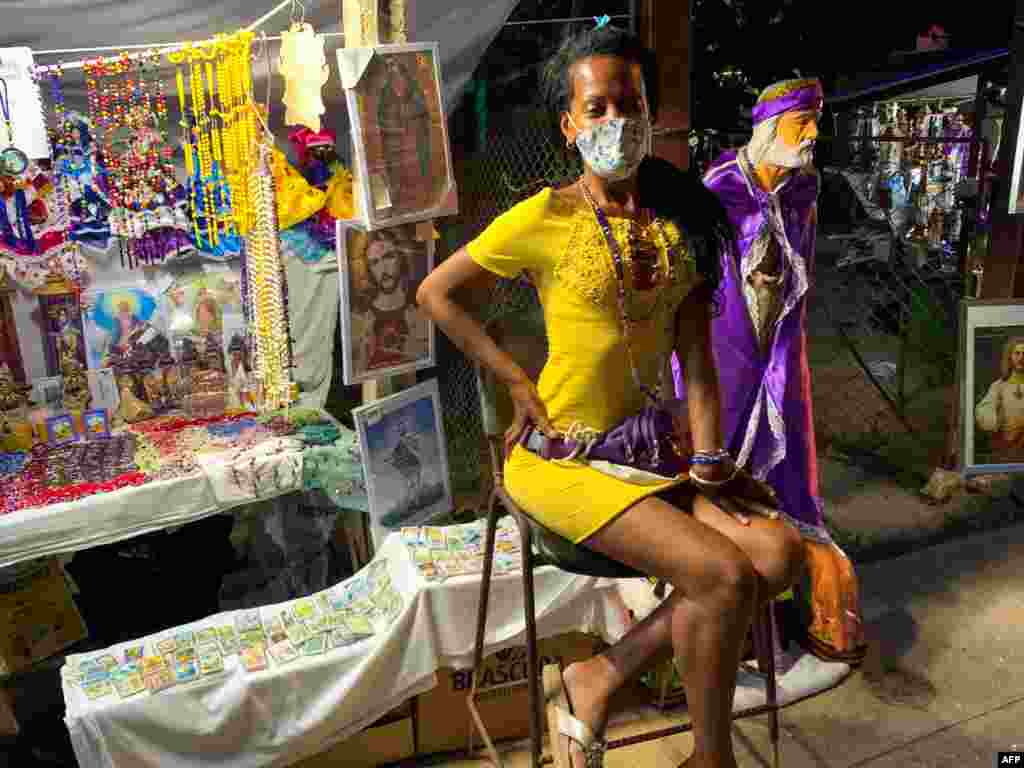 Una vendedora de imágenes religiosas espera a los clientes durante la procesión de San Lázaro, en El Rincón, La Habana, Cuba, el 17 de diciembre de 2020. (Foto de ADALBERTO ROQUE / AFP)
