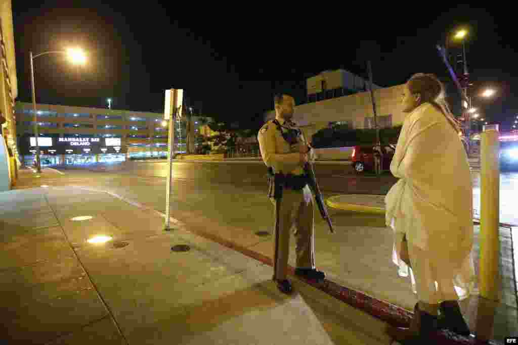 Un agente de policía permanece en guardia junto a una mujer envuelta en una manta, ante el hotel Mandalay Bay, cerca de donde se produjo el tiroteo.